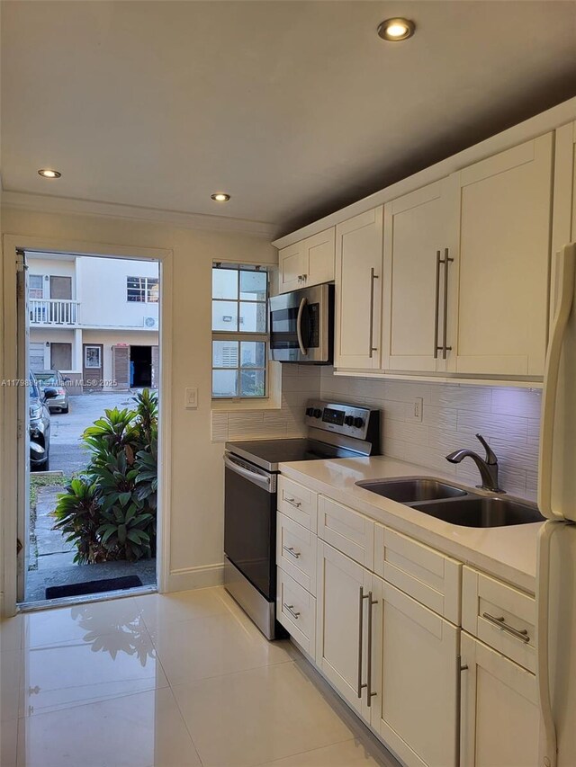 kitchen featuring stainless steel appliances, a sink, tasteful backsplash, white cabinetry, and recessed lighting