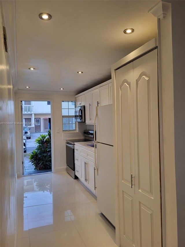 kitchen with freestanding refrigerator, electric stove, stainless steel microwave, white cabinets, and recessed lighting