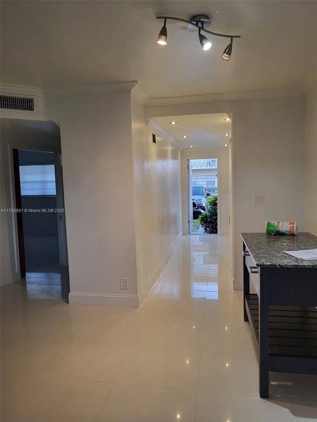 hall featuring ornamental molding, light tile patterned flooring, and baseboards