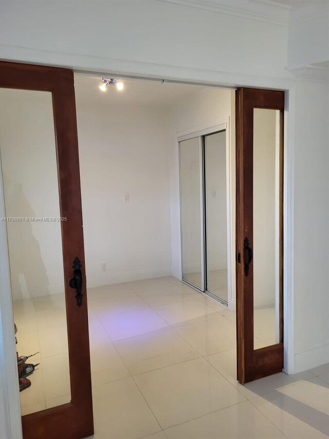 corridor featuring light tile patterned floors, ornamental molding, and baseboards