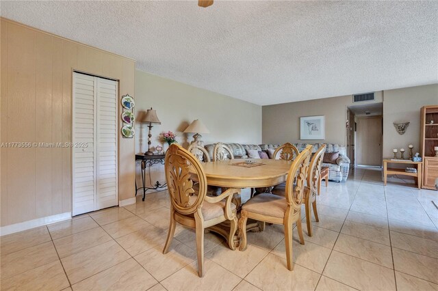922 NE 199th St Unit 206, Miami, FL 33179 - dining space with light tile patterned floors, baseboards, a textured ceiling, and wood walls