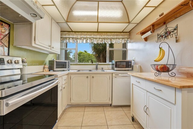 922 NE 199th St Unit 206, Miami, FL 33179 - kitchen with appliances with stainless steel finishes, under cabinet range hood, a sink, light tile patterned floors, and butcher block countertops