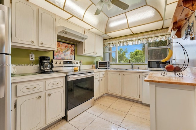 kitchen featuring stainless steel appliances, a sink, under cabinet range hood, light countertops, and light tile patterned floors
