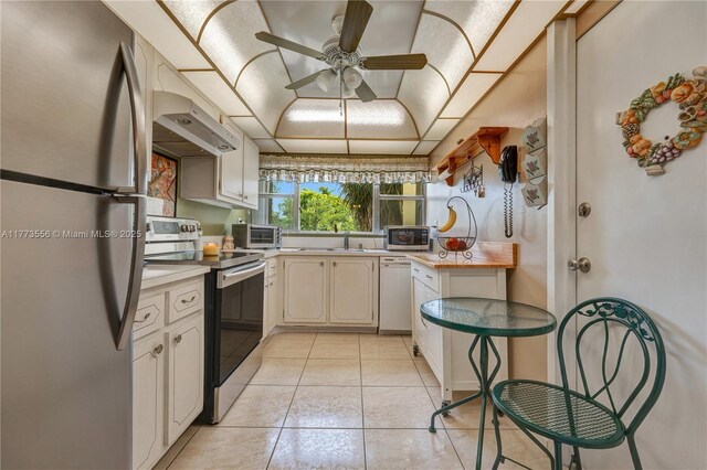 922 NE 199th St Unit 206, Miami, FL 33179 - kitchen featuring appliances with stainless steel finishes, light tile patterned floors, ceiling fan, under cabinet range hood, and a sink