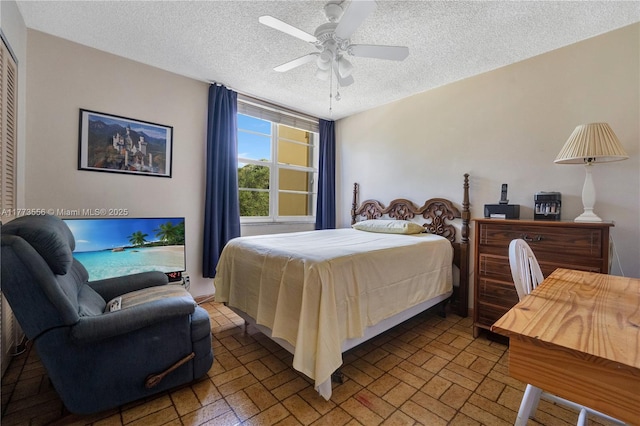bedroom featuring a textured ceiling, a ceiling fan, and brick patterned flooring
