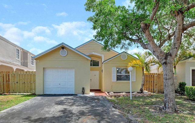 view of front of property featuring an attached garage, stucco siding, asphalt driveway, and fence