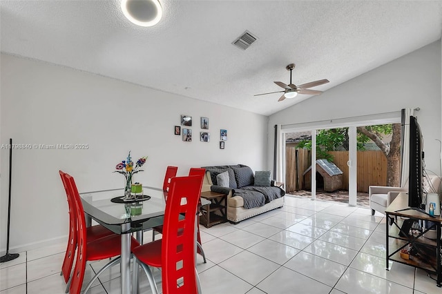 dining space with ceiling fan, a textured ceiling, lofted ceiling, and light tile patterned floors