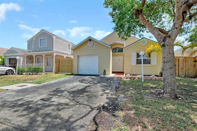 view of front of house with asphalt driveway, an attached garage, fence, and stucco siding