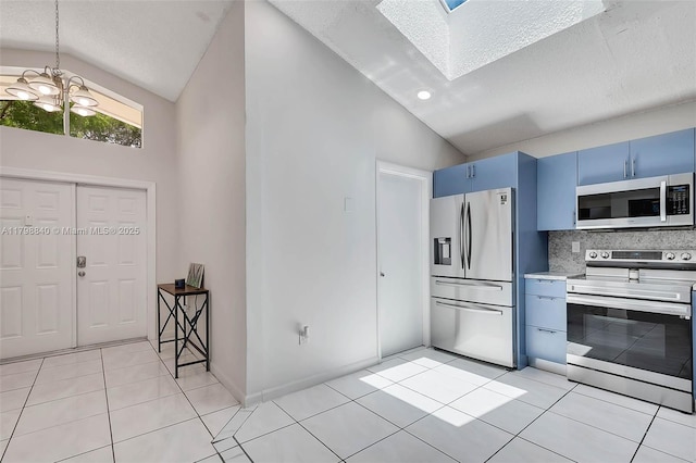 kitchen featuring stainless steel appliances, blue cabinets, vaulted ceiling, a skylight, and decorative backsplash