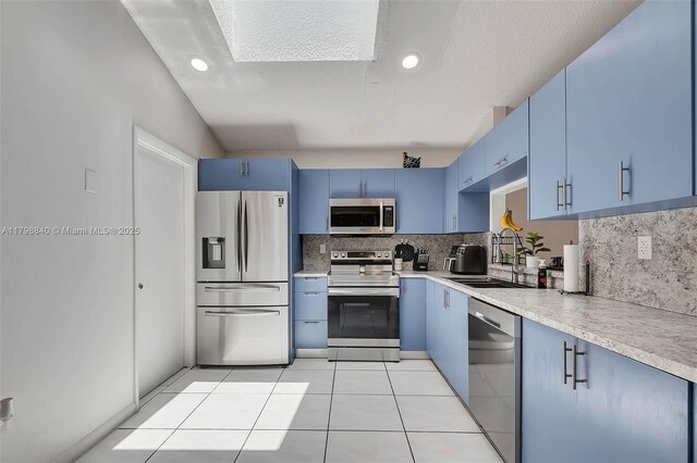 kitchen with appliances with stainless steel finishes, blue cabinets, a sink, backsplash, and recessed lighting