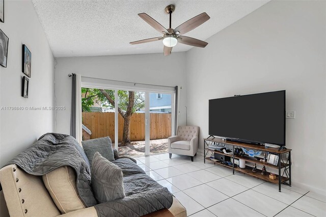 living area featuring lofted ceiling, light tile patterned flooring, ceiling fan, and a textured ceiling