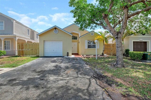 ranch-style home with an attached garage, driveway, fence, and stucco siding