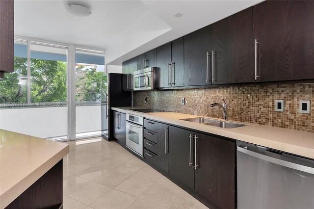 kitchen featuring appliances with stainless steel finishes, a sink, backsplash, and light countertops