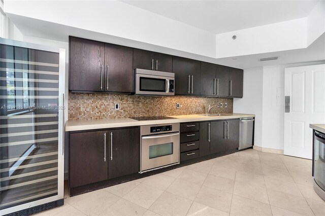 kitchen with stainless steel appliances, light countertops, a sink, decorative backsplash, and wine cooler