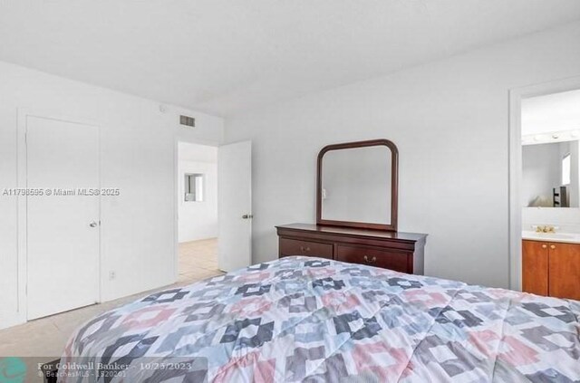 bedroom with connected bathroom and tile patterned flooring