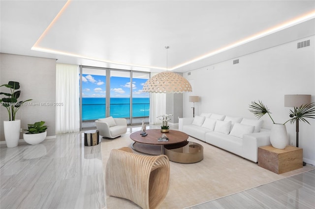 living room featuring floor to ceiling windows, a water view, and baseboards