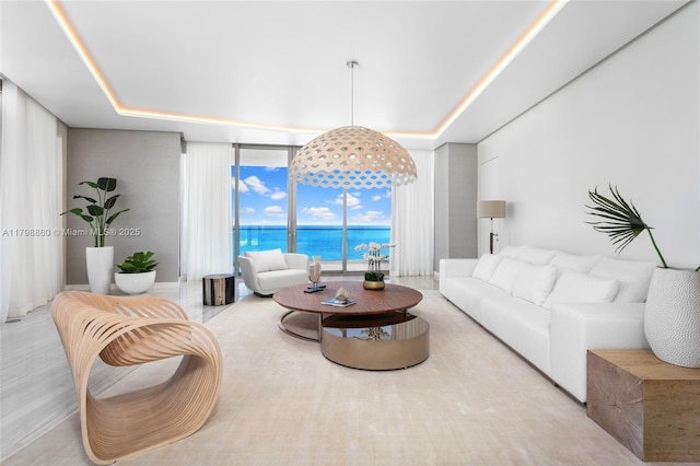 living area with a water view, a raised ceiling, and a wall of windows