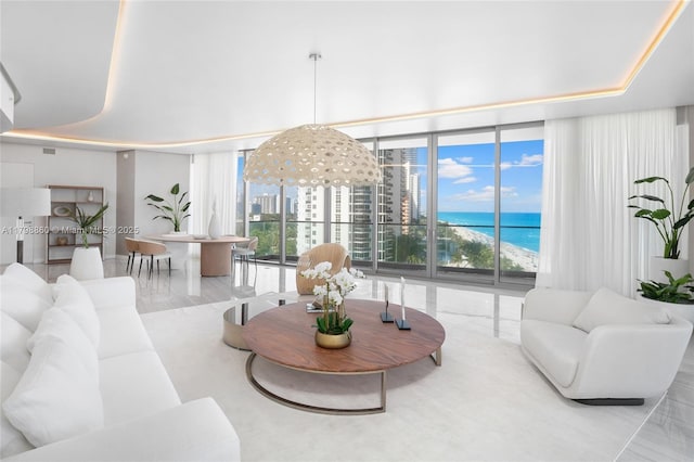 living area featuring floor to ceiling windows, a water view, and a high ceiling