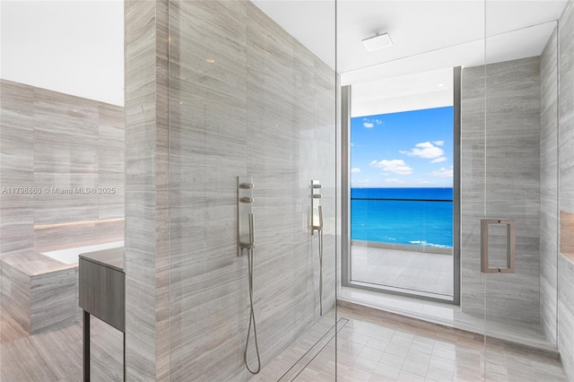 bathroom with a shower stall, tile walls, and tile patterned flooring