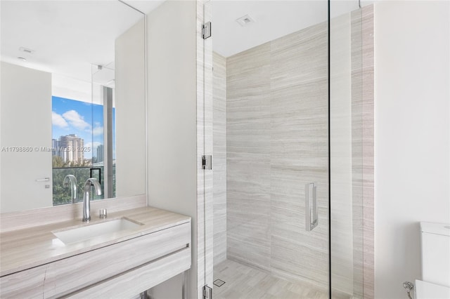 bathroom with a shower stall, vanity, a view of skyline, and toilet