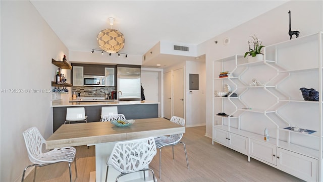 dining room with light wood-style flooring, electric panel, and baseboards
