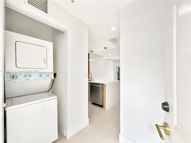 washroom with stacked washer / dryer, light wood-style floors, baseboards, and recessed lighting