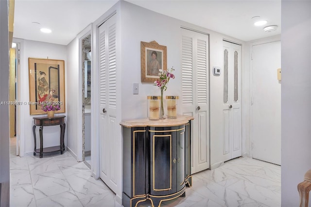 corridor featuring light marble finish floors, baseboards, and recessed lighting
