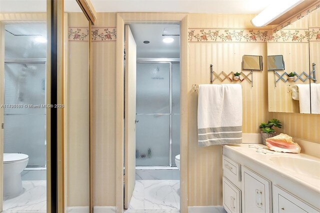 bathroom featuring toilet, marble finish floors, a stall shower, and vanity