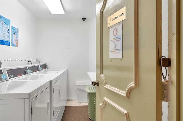 shared laundry room featuring washing machine and dryer, light tile patterned flooring, and baseboards