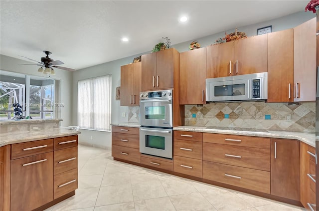 12672 Tucano Cir, Boca Raton, FL 33428 - kitchen with appliances with stainless steel finishes, decorative backsplash, brown cabinets, light stone counters, and recessed lighting