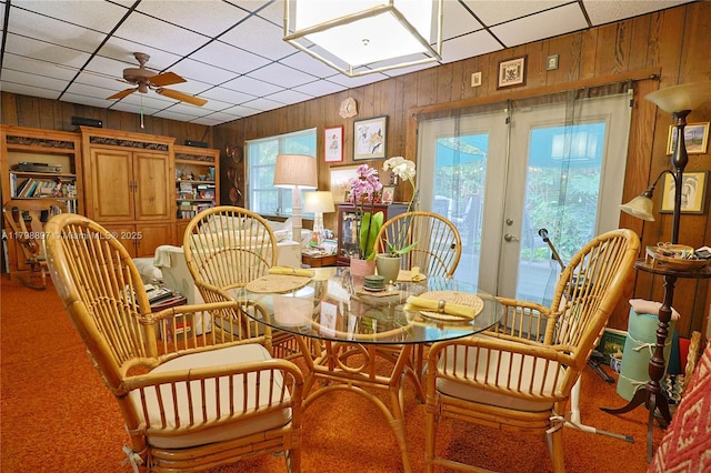 10610 SW 103rd St, Miami, FL 33176 - carpeted dining space featuring wood walls, healthy amount of natural light, a ceiling fan, a paneled ceiling, and french doors