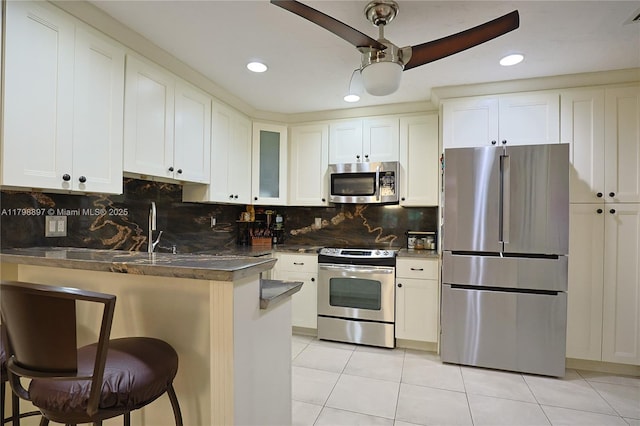 10610 SW 103rd St, Miami, FL 33176 - kitchen featuring stainless steel appliances, dark countertops, a peninsula, light tile patterned floors, and glass insert cabinets