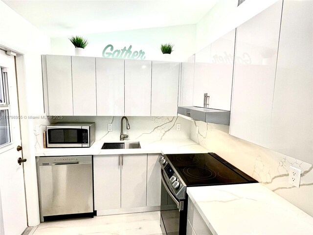 2406 Marathon Ln, Fort Lauderdale, FL 33312 - kitchen featuring stainless steel appliances, a sink, under cabinet range hood, backsplash, and modern cabinets