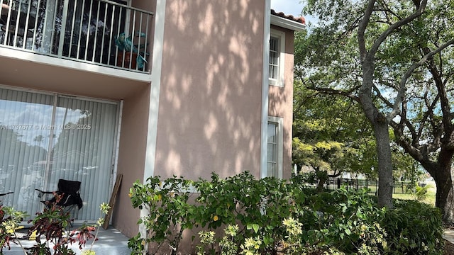 view of side of home with stucco siding and a balcony