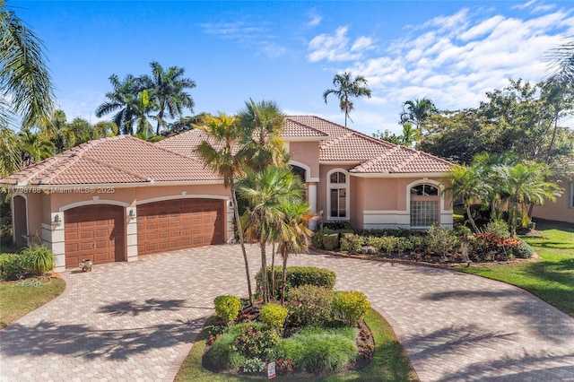 8100 Muirhead Cir, Boynton Beach, FL 33472 - mediterranean / spanish-style house with an attached garage, stucco siding, decorative driveway, and a tiled roof