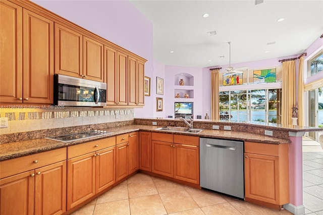 8100 Muirhead Cir, Boynton Beach, FL 33472 - kitchen featuring stainless steel appliances, a peninsula, light tile patterned floors, brown cabinetry, and recessed lighting