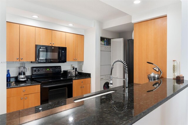6917 Collins Ave Unit 607, Miami Beach, FL 33141 - kitchen with black appliances, stacked washer / dryer, dark stone countertops, and recessed lighting