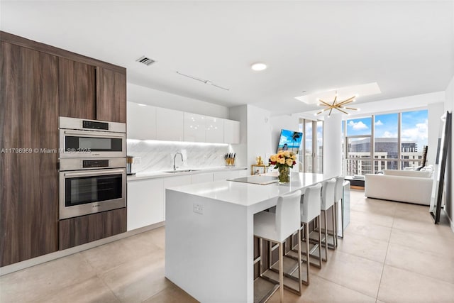 851 NE 1st Ave Unit 4011, Miami, FL 33132 - kitchen featuring double oven, a sink, modern cabinets, light countertops, and white cabinetry