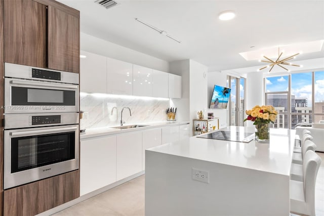 851 NE 1st Ave Unit 4011, Miami, FL 33132 - kitchen featuring a sink, double oven, modern cabinets, black electric cooktop, and decorative backsplash