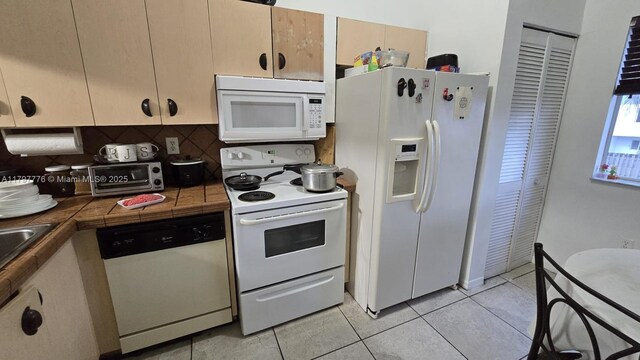 6425 SW 130th Pl Unit 704, Miami, FL 33183 - kitchen featuring white appliances, tile counters, decorative backsplash, and light tile patterned floors
