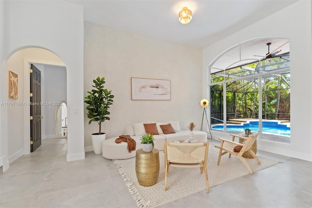 10275 Oak Meadow Ln, Lake Worth, FL 33449 - living room featuring a sunroom, arched walkways, concrete floors, baseboards, and ceiling fan