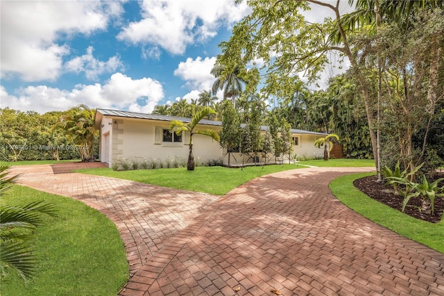 615 NE 115th St, Biscayne Park, FL 33161 - view of front of property with decorative driveway, a front lawn, a standing seam roof, stucco siding, and metal roof