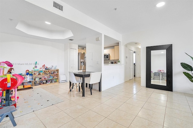interior space featuring light tile patterned flooring, arched walkways, recessed lighting, and a tray ceiling
