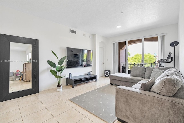 tiled living room with a textured ceiling and baseboards