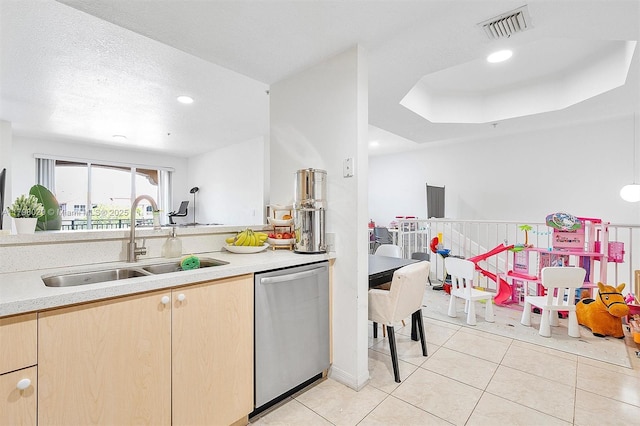 kitchen with stainless steel dishwasher, a sink, light countertops, light brown cabinetry, and recessed lighting