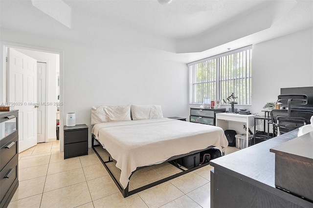 bedroom with light tile patterned floors and a tray ceiling