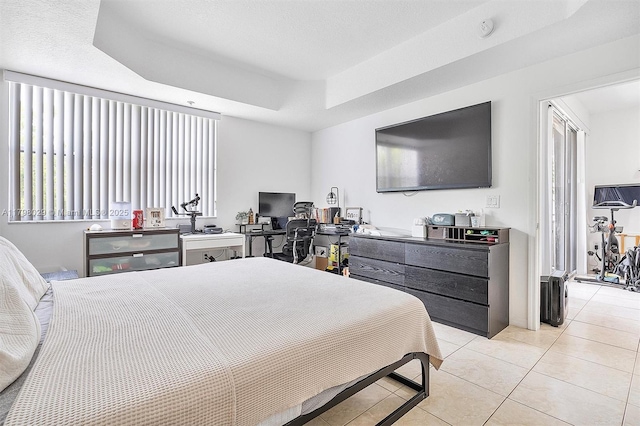 bedroom featuring a raised ceiling, light tile patterned floors, and an office area