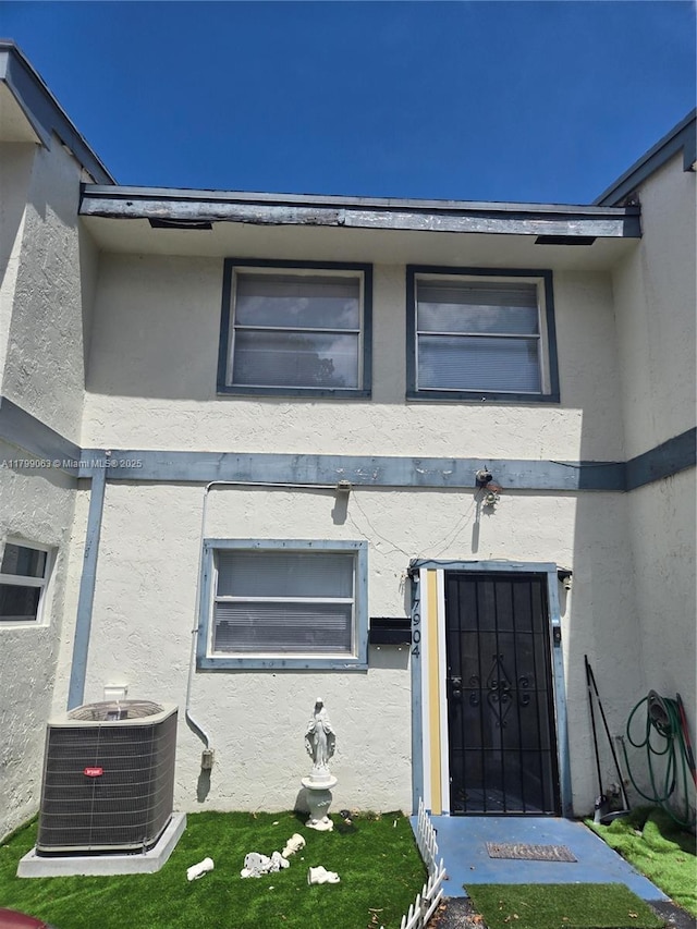 property entrance featuring stucco siding and central air condition unit