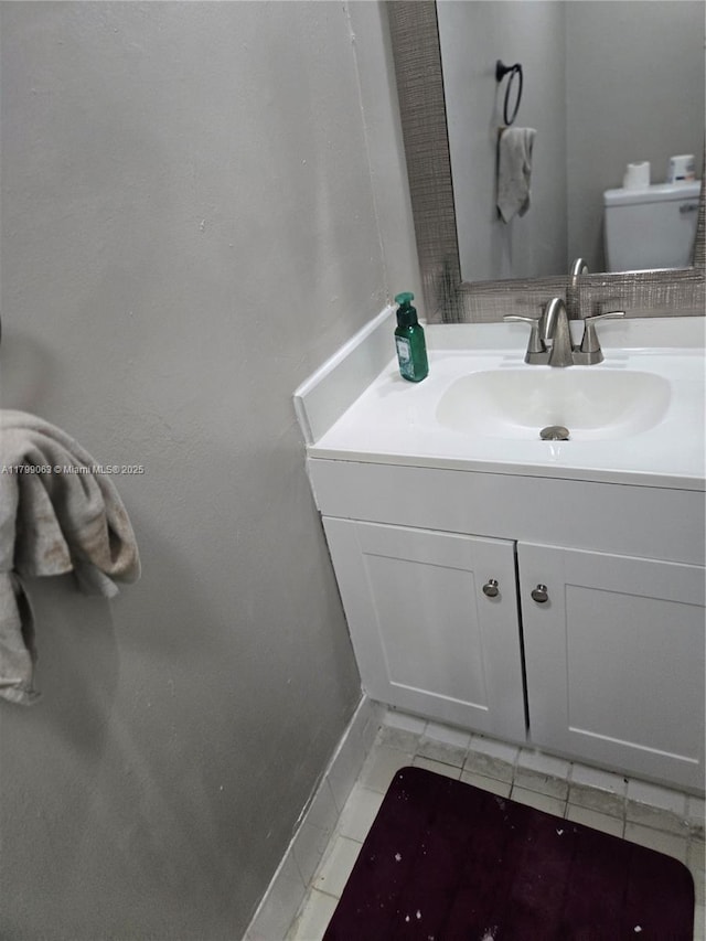 bathroom with vanity, baseboards, tile patterned flooring, and toilet