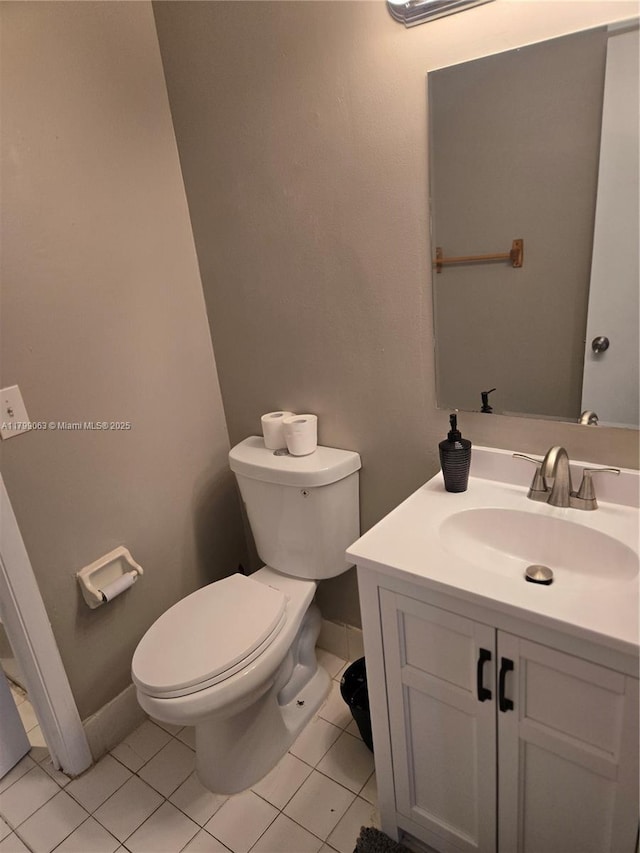 half bathroom featuring toilet, vanity, tile patterned floors, and baseboards